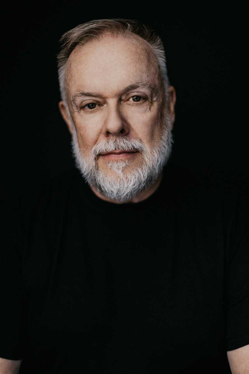A headshot of Patrick Raftery wearing a black shirt in 2023.