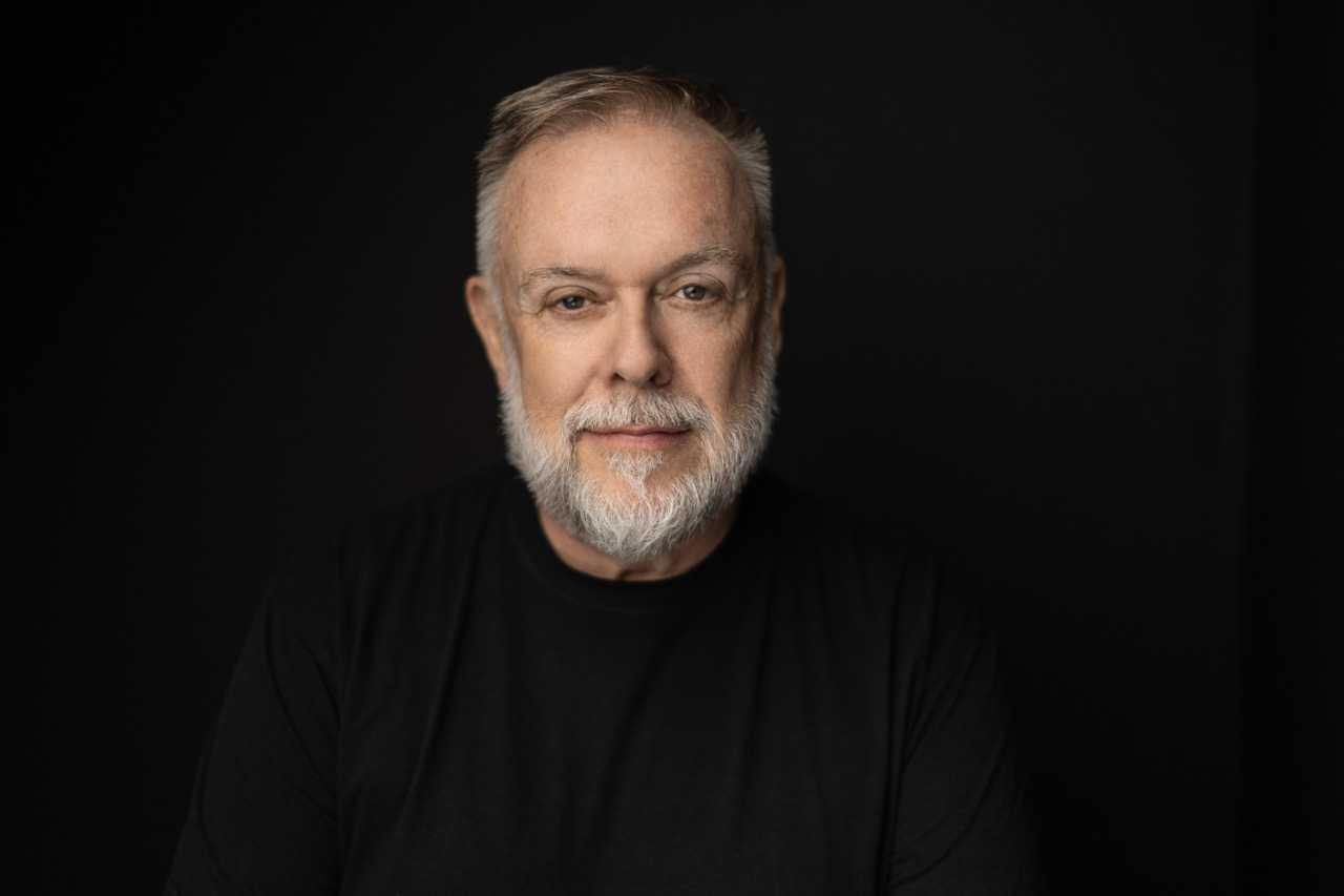 A headshot of Patrick Raftery wearing a black shirt in 2023.